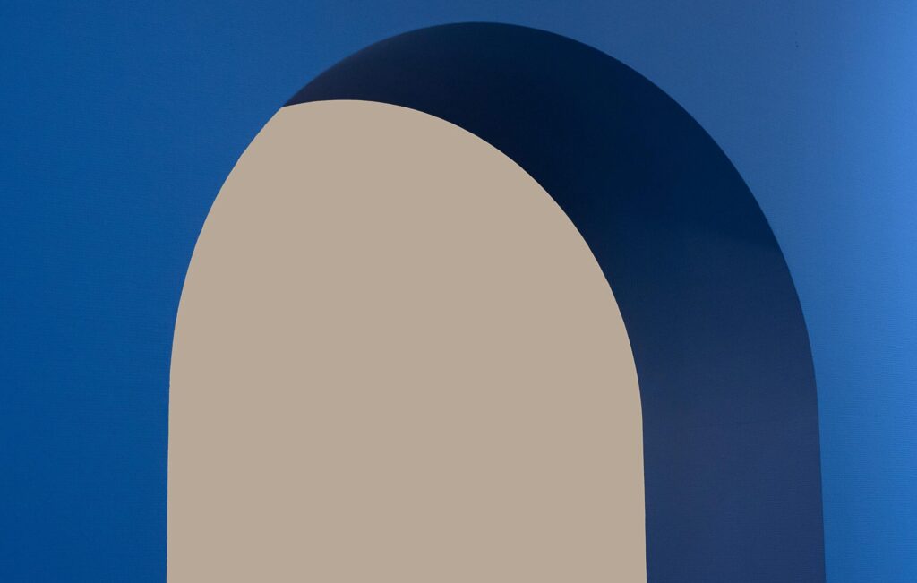 Minimalist abstract image featuring a blue arch against a beige background.